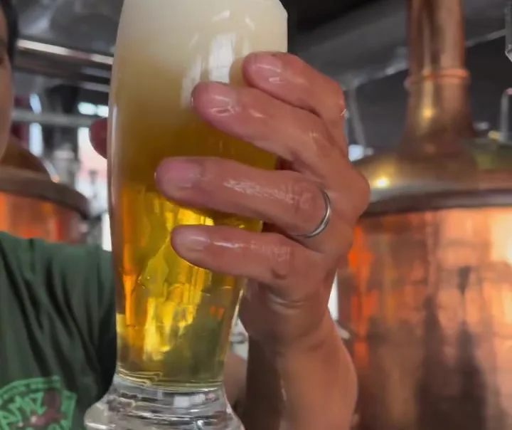 Beer poured fresh beside the copper brewing tanks
